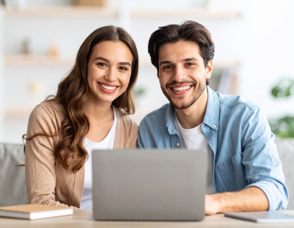 Zwei fröhliche Studenten hinter einem Laptop